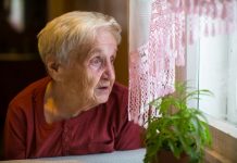 Older Woman With Longing Looks Out The Window.