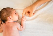 Newborn Baby Securely Grasping His Mother's Hands, Close Up Fingers.