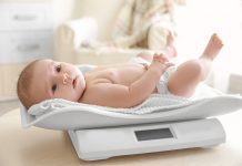 Cute Little Baby Lying On Scales At Home
