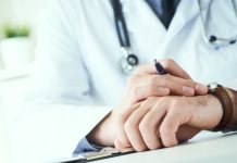 Man Doctor With Stethoscope Looking At Wrist Watch. Doctor In White Uniform At Office Background Waiting For Patients. Time To Visit Therapist.