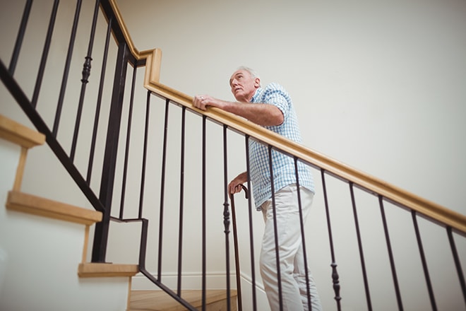Senior Man Climbing Upstairs With Walking Stick