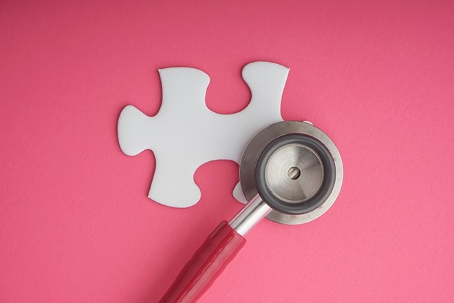 Stethoscope And White Jigsaw Puzzle On Pink Background. Copy Space