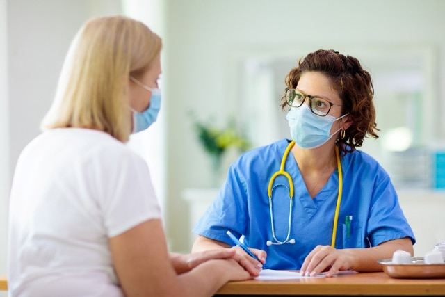 Doctor Examining Sick Patient. Ill Woman In Clinic