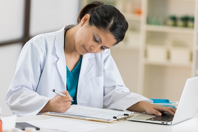 Serious Mid Adult Female Pharmacist Concentrates While Working On Paperwork