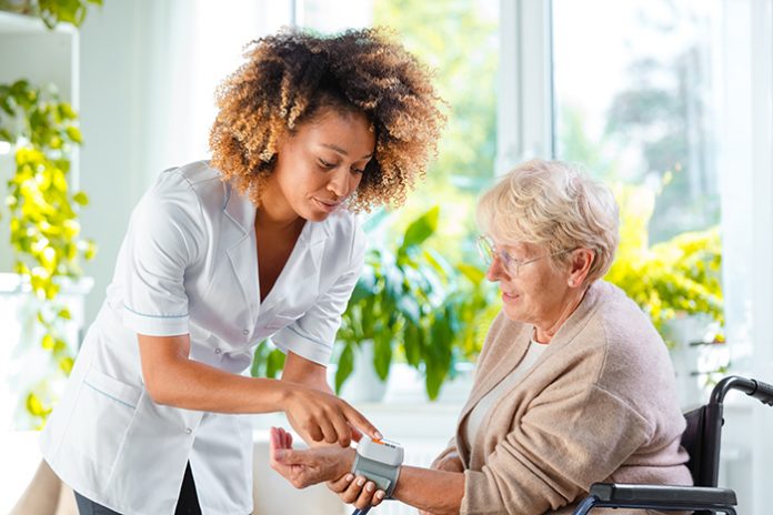 Home Nurse Checking The Blood Pressure Of The Elderly Lady