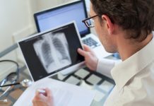 Doctor Looking At X Ray Of Lungs And Writing Diagnosis