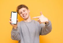 Happy Boy Is Standing On A Yellow Background, Looks Into The Cam