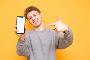 Happy Boy Is Standing On A Yellow Background, Looks Into The Cam