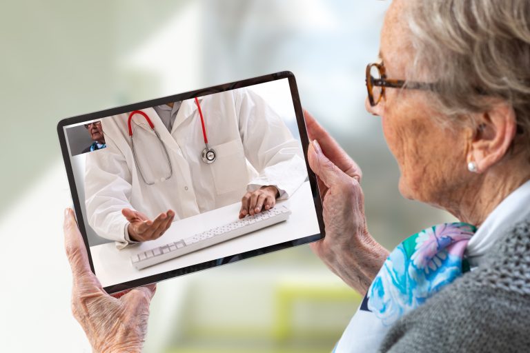 Senior Woman Consults A E Health Doctor With Tablet Computer Sitting In Soft Chair. In Touchscreen, Male Doctor: With Telehealth Application Patient Can Reach Relevant Specialist Remotely.