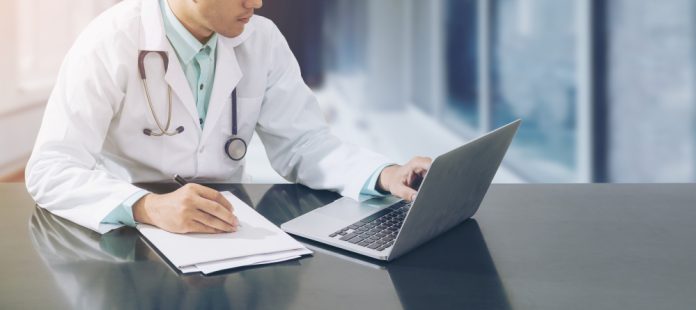 Doctor Working On Desk With Laptop