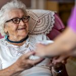 Helpful home healthcare nurse gives a senior female a cup of hot tea