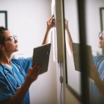 Side view of smiling middle aged nurse checking X-ray in a docto