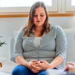 A shy overweight woman on a consulting with a psychotherapist, feeling sad.