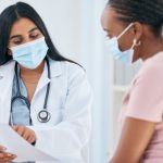 Doctor, covid mask and woman patient medical results in a health consultation in a clinic office. Diversity of women in a hospital, nurse and healthcare appointment with coronavirus consulting check