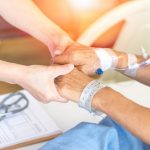 Elderly female hand holding hand of young caregiver at nursing home.Geriatric doctor or geriatrician concept. Doctor physician hand on happy elderly senior patient to comfort in hospital examination