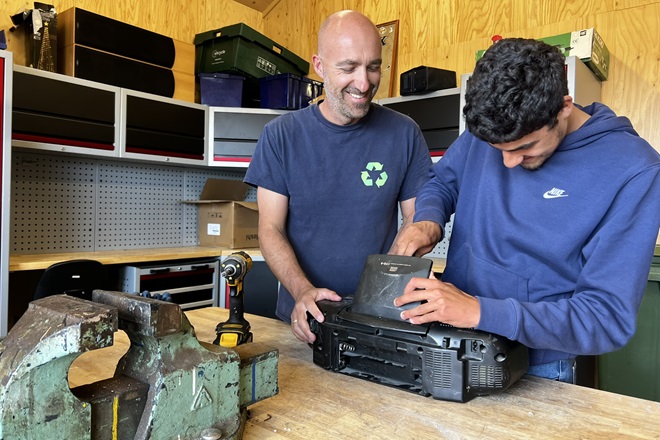 In de demontageloods van de ecostraat halen begeleider Patrick en deelnemer Dani een oude radio uit elkaar.